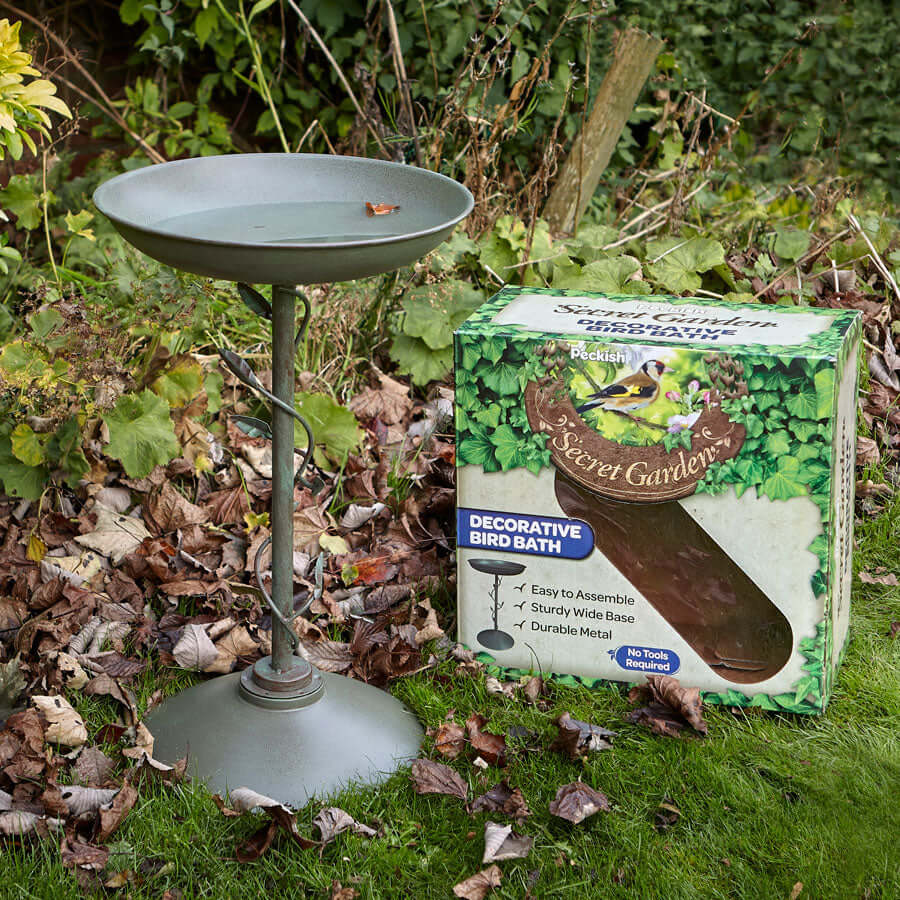 Decorative, silver bird bath next to it's packaging with a goldfinch on the front.